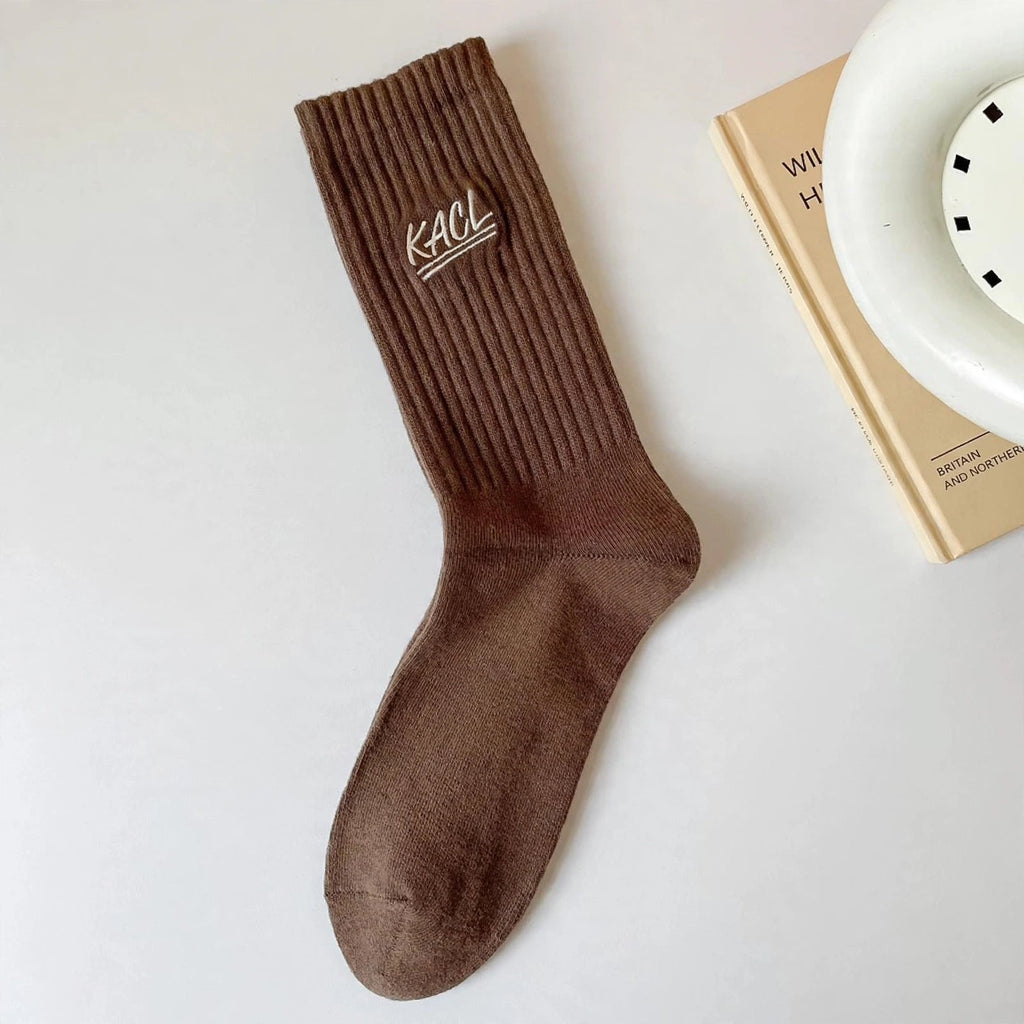Chaussettes blanches côtelées KACL portées, logo KACL visible